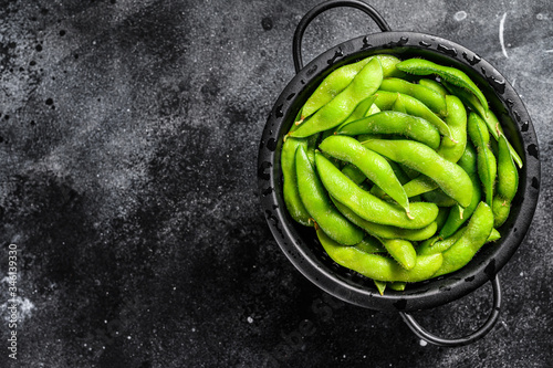 Raw beans edamame in the colander. Black background. Top view. Copy space photo