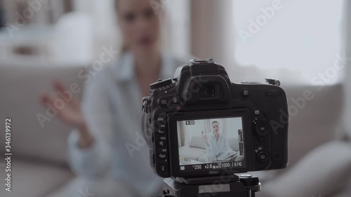 Young smiling videobloger girl is pointing at camera in living room photo