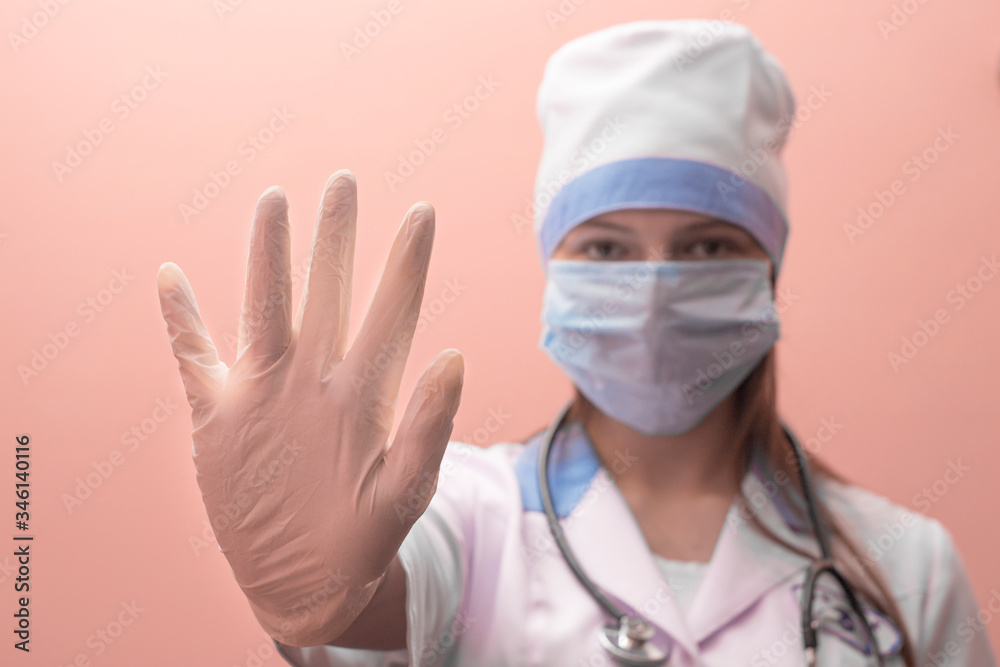 young and frowning woman doctor with a stethoscope around her neck shows a stop sign with her hand young and frowning woman doctor with a stethoscope around her neck shows a stop sign with her hand