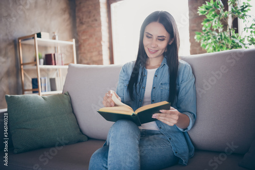 Photo of homey lady read exciting historic novel interested book worm sitting comfy couch stay home safety quarantine corona virus disease casual clothes living room indoors
