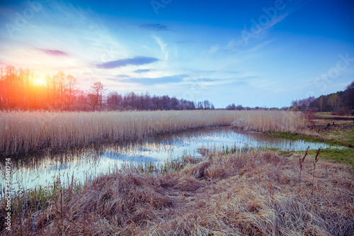 Magical sunset in the countryside. Rural landscape in spring. Narrow river in the evening