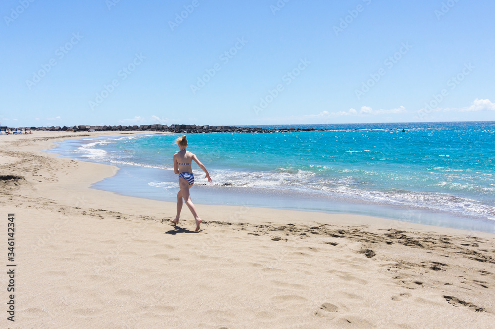 Girl teen having fun at the empty beach in sunny weather . Crisis in turism. 