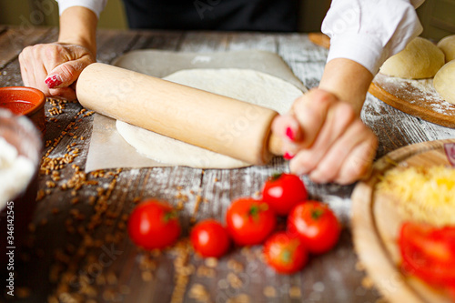 Woman's hands roll out the dough on a table