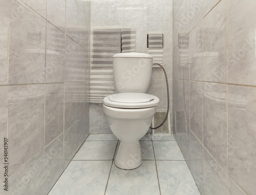 Toilet bowl in tiny toilet room with tile wall decorations