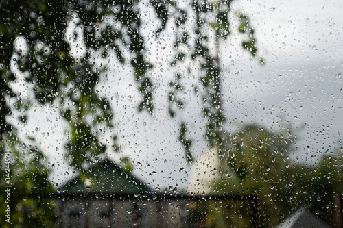 Raindrops on window pane. Blurred background outside the window in the rain.