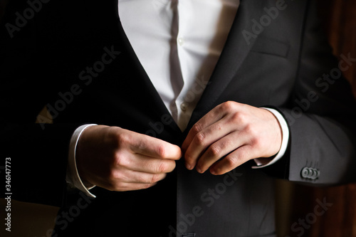 Businessman in suit fastens his jacket. Smart casual outfit. Man getting ready for work. groom in a jacket, the groom fastens his jacket. The morning of the groom, bridegroom's fees