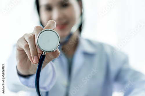 Medical concept of Asian female doctor in white coat with stethoscope working in office in hospital.