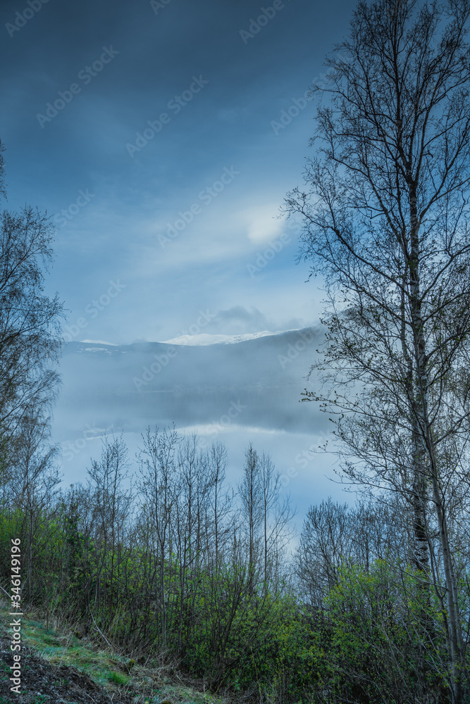 Widok na szczyt górski odbijający się w jeziorze w mglisty poranek w okolicach miejscowości Norfjell