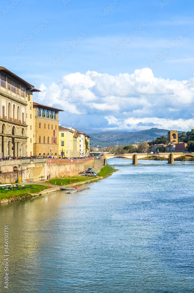 Cityscape of beautiful Florence, Tuscany, Italy photographed from the famous Ponte Vecchio Bridge. Historical buildings including Galleria degli Uffizi along the Arno river. Vertical photo