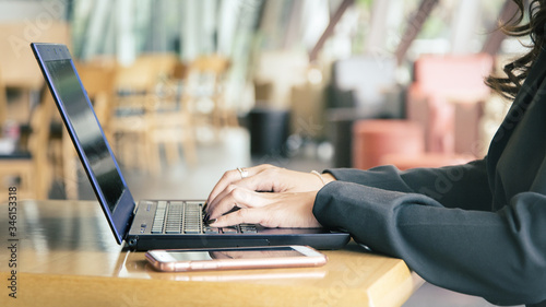 Female office worker typing on the keyboard.Woman using laptop in cafe close up.Young business woman working on her laptop.