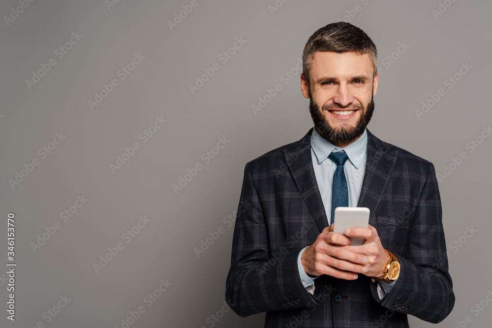 happy handsome bearded businessman in suit using smartphone on grey background happy handsome bearded businessman in suit using smartphone on grey background