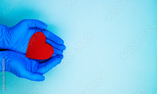 red heart in hands in blue medical gloves on a blue background. background for the day of the medic, top view, space for text