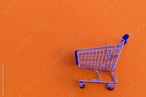 Empty shopping cart on orange background.