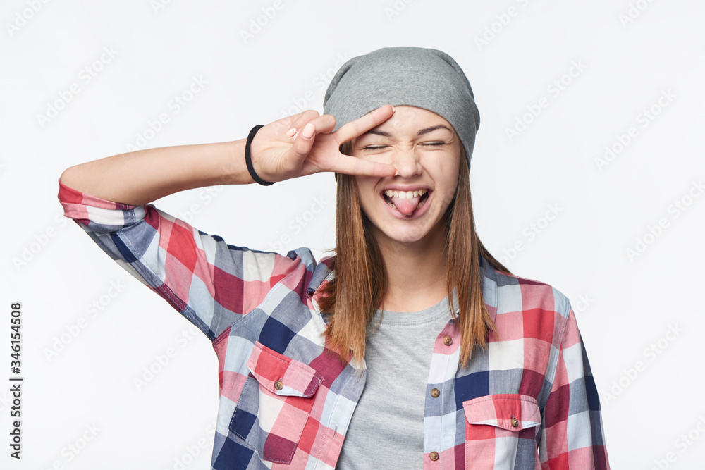 Closeup of funky teen girlshowing peace sign and her tongue Closeup of funky teen girlshowing peace sign and her tongue