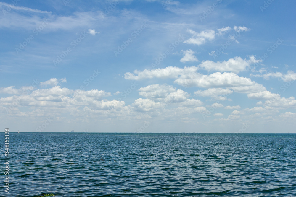 Wide open shot of a calm ocean with cloudy blue sky on Florida coast Wide open shot of a calm ocean with cloudy blue sky on Florida coast