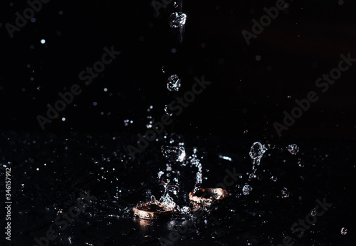 wedding rings with the water splash on black background