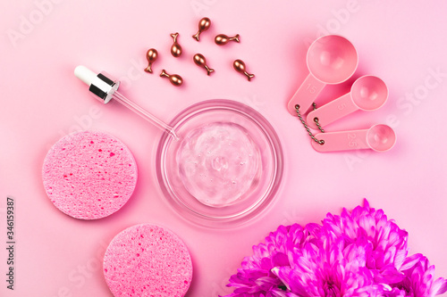 Beauty accessories for home spa. Flat lay on pink background. Hyaluronic gel, cosmetic ampoules, pipette, sponges, measuring spoons, flowers. Salon wellness procedures, beauty routine, mask, face care