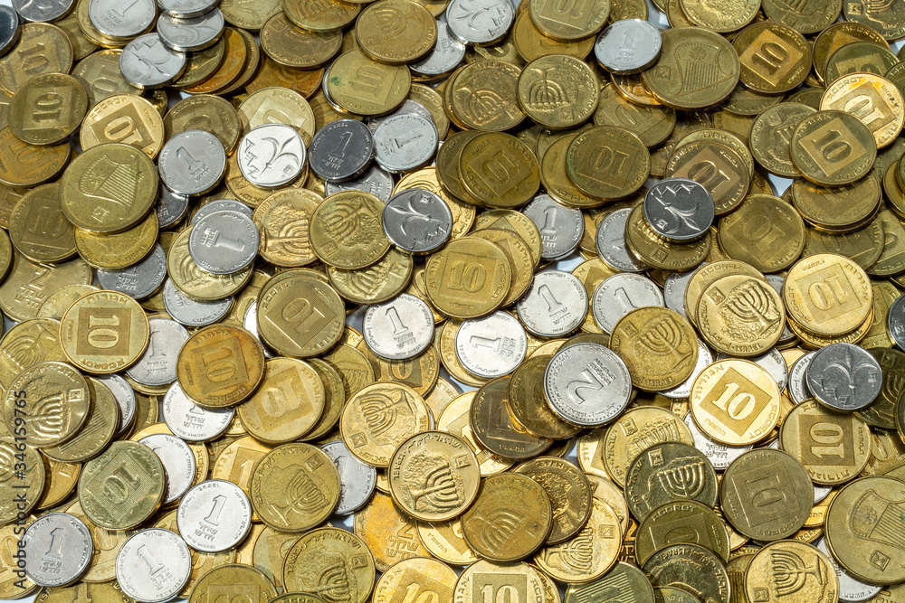 Money. A pile of coins of different denominations lies on a white background. All money is new Israeli shekels. Money. A pile of coins of different denominations lies on a white background. All money is new Israeli shekels.