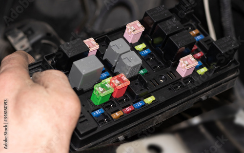 Several rows of fuses in the automotive fuse box, auto electricians repair, specialist, hand, color fuses