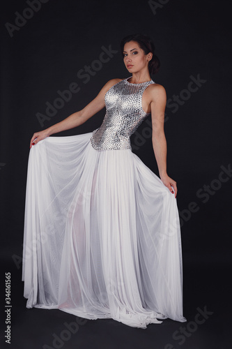 Pretty girl posing in a fashion dress over black background