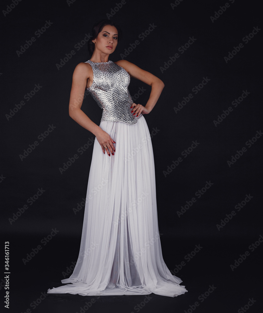 Pretty girl posing in a fashion dress over black background