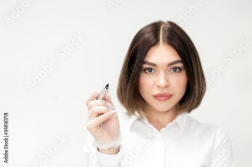 Microblading tools used for applying permanent eyebrow makeup. Brow tattoo application tools. The master holds in hands a professional apparatus for working with eyebrows. Portrait of a girl. Close up