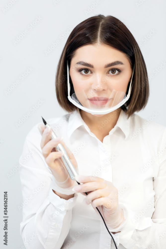 Microblading tools used for applying permanent eyebrow makeup. Brow tattoo application tools. Master holds in hands a professional apparatus for working with brows. Portrait girl at work. Close up Microblading tools used for applying permanent eyebrow makeup. Brow tattoo application tools. Master holds in hands a professional apparatus for working with brows. Portrait girl at work. Close up