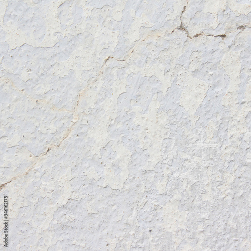 the white wall of an old house with beautiful cracks from time. white paint and whitewash on the wall. the background is white with soft blue and yellow. white old wall background