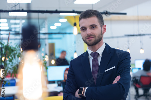 Portrait of young bearded Caucasian businessman dressed smart casual posing inside modern coworking space.