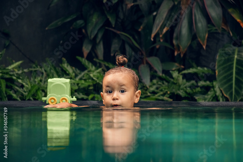 a child, a beautiful little girl poses in an outdoor tropical pool on the island of Bali. The concept of summer holidays and travel.
