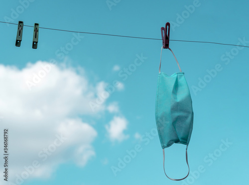 mask hanging on a clothespin against a blue sky