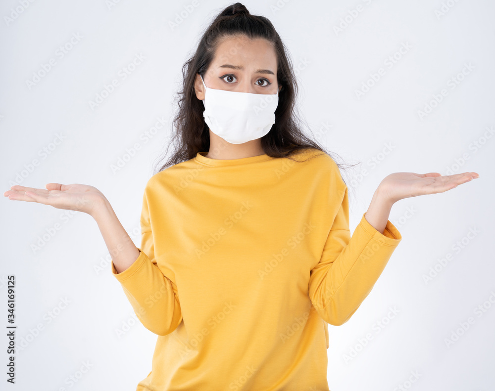 Young Worry Asian woman wearing hygienic mask to prevent infection corona virus hands feels confused pose wearing a yellow sweater shoot in isolated on white background Young Worry Asian woman wearing hygienic mask to prevent infection corona virus hands feels confused pose wearing a yellow sweater shoot in isolated on white background