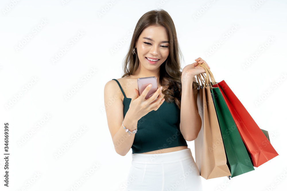 Young Asian woman using smart phone and holding shopping bag shoot in isolate white background. shopping payment concept Young Asian woman using smart phone and holding shopping bag shoot in isolate white background. shopping payment concept