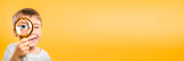 Child see through magnifying glass on the color yellow backgrounds. Big kid eye