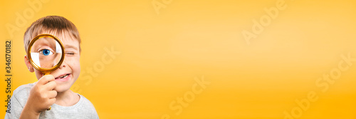 Child see through magnifying glass on the color yellow backgrounds. Big kid eye