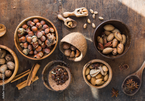Assortment of nuts in a wooden bowl, on a wooden background. pecans, hazelnuts, almonds, pine nuts, brazil nut, cashews in shell. Top view, flat lay.