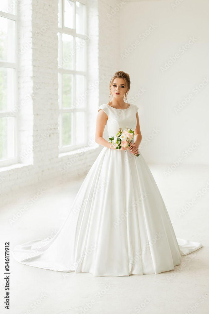 bride in white wedding dress. happy beautiful young woman in white traditional wedding dress on white background. big windows and white walls. bride in white wedding dress. happy beautiful young woman in white traditional wedding dress on white background. big windows and white walls.