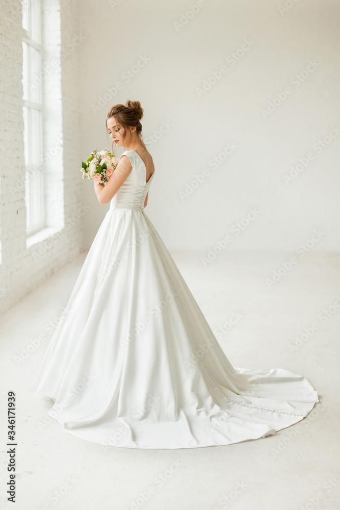 bride in white wedding dress. happy beautiful young woman in white traditional wedding dress on white background. big windows and white walls. bride in white wedding dress. happy beautiful young woman in white traditional wedding dress on white background. big windows and white walls.