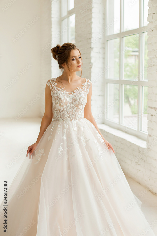 bride in white wedding dress. happy beautiful young woman in white traditional wedding dress on white background. big windows and white walls. bride in white wedding dress. happy beautiful young woman in white traditional wedding dress on white background. big windows and white walls.