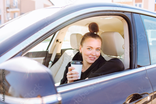 Beautiful young lady sitting in car and drinking coffee take off © Olga