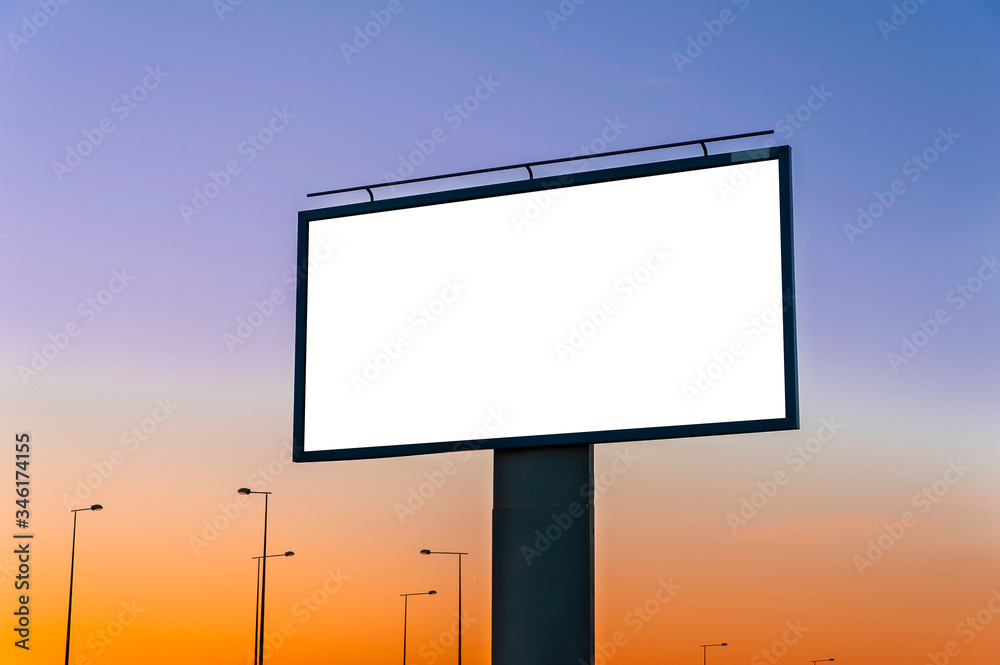 Fototapeta premium Blank white billboard for advertisement near the road at dusk