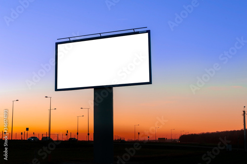 Blank white billboard for advertisement near the road at dusk