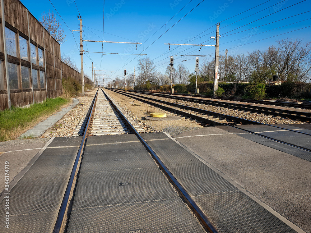 Under clear skies, the railway line can be seen. The multiple railway tracks are viewed from the middle and continue into the distance.