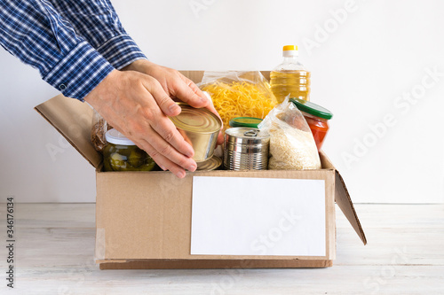 Cardboard box with oil, canned food, cereals and pasta.
