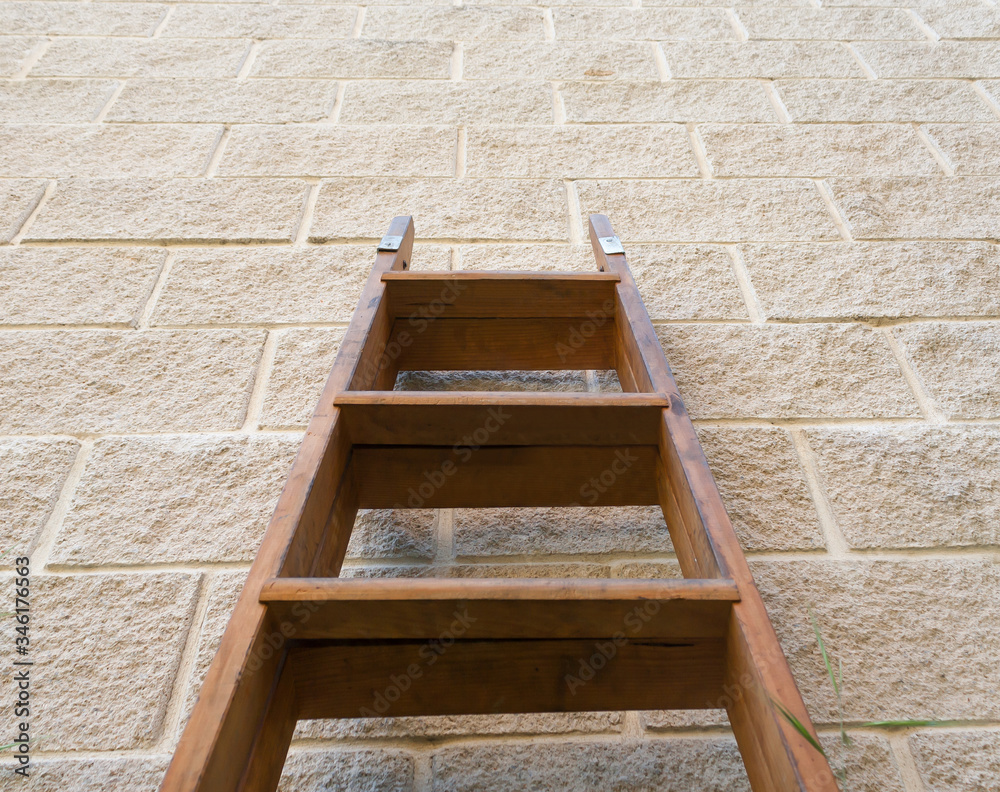 Old wooden ladder leaning against the wall, low angle view Old wooden ladder leaning against the wall, low angle view