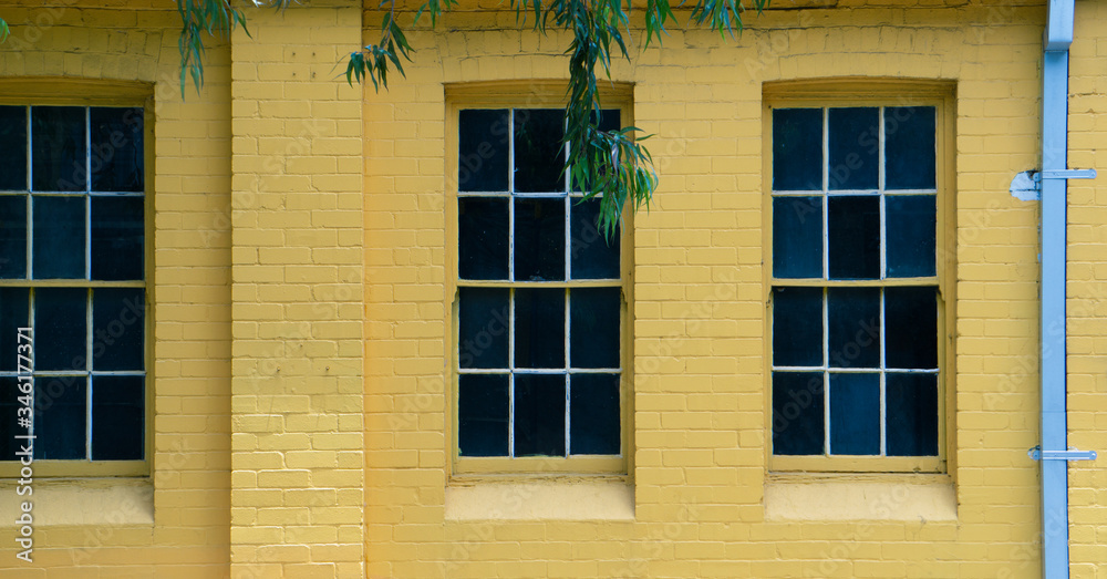 Single-hang windows in a yellow brick wall.
