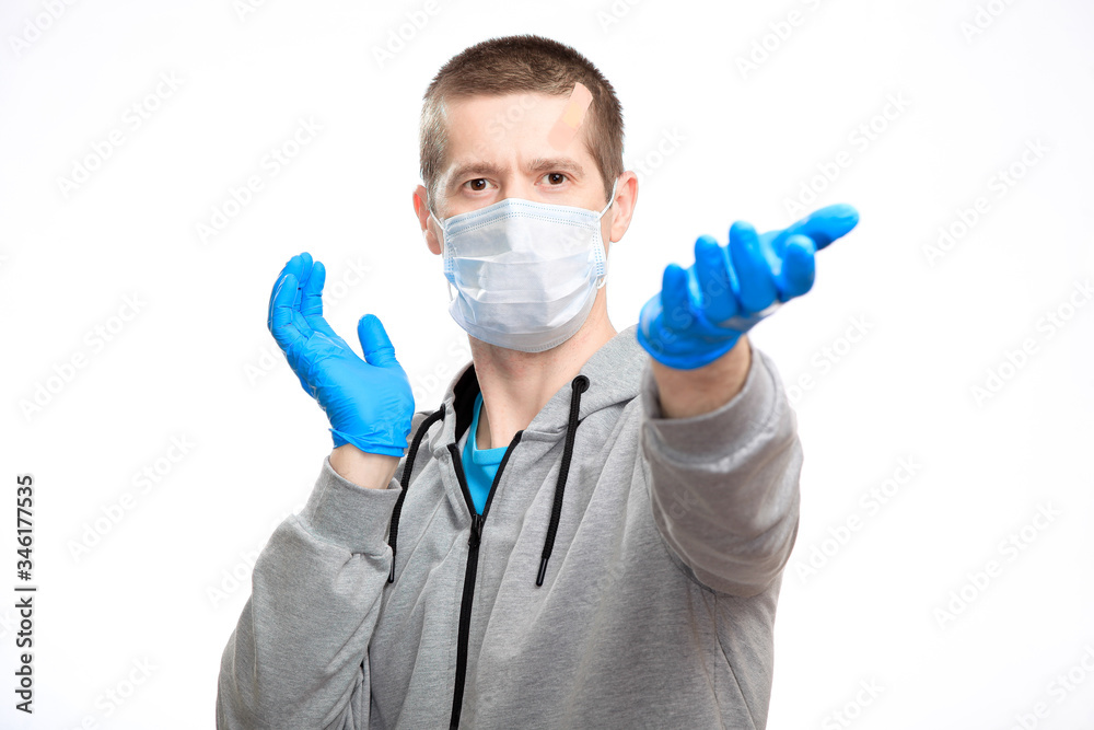 A man in a medical mask reaches out in rubber gloves, wears a sports jacket and looks into the camera. Close-up, isolated A man in a medical mask reaches out in rubber gloves, wears a sports jacket and looks into the camera. Close-up, isolated