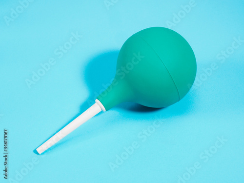 Medical syringe with a green pear and a white tip on a blue background