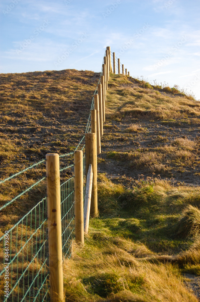 A wire and wood fence leading path up a steep cliff