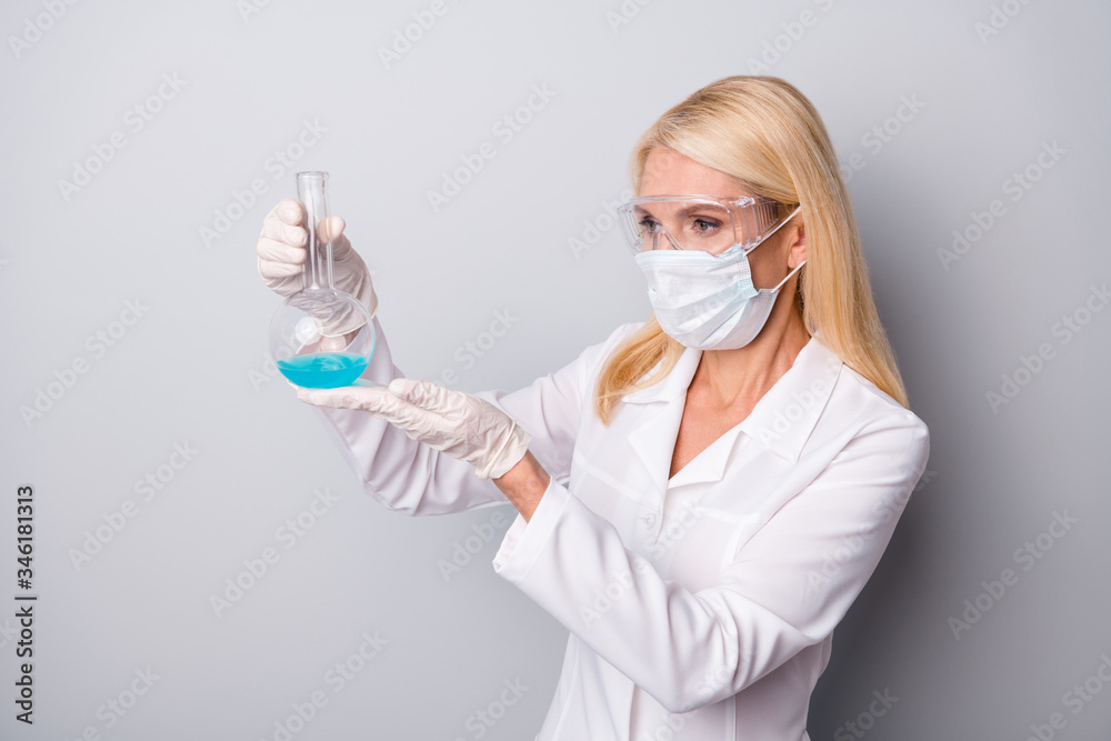 Portrait of focused concentrated pensioner retired woman scientist wear medical mask latex gloves goggles check chemical want make corona virus antidote isolated over gray color background